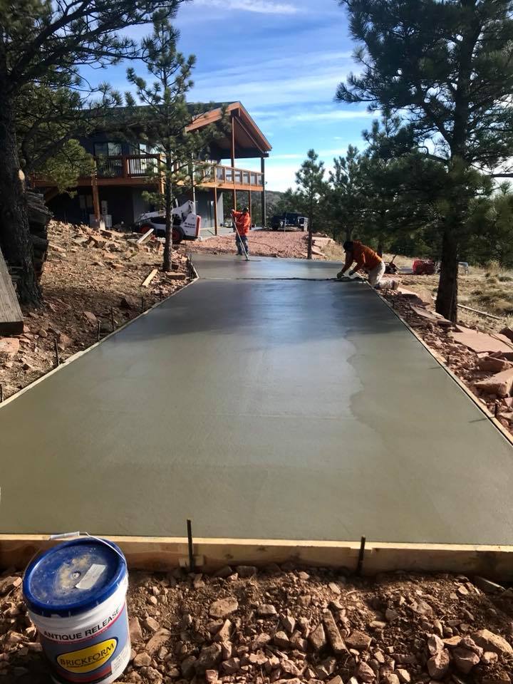 Workers smoothing freshly poured concrete driveway